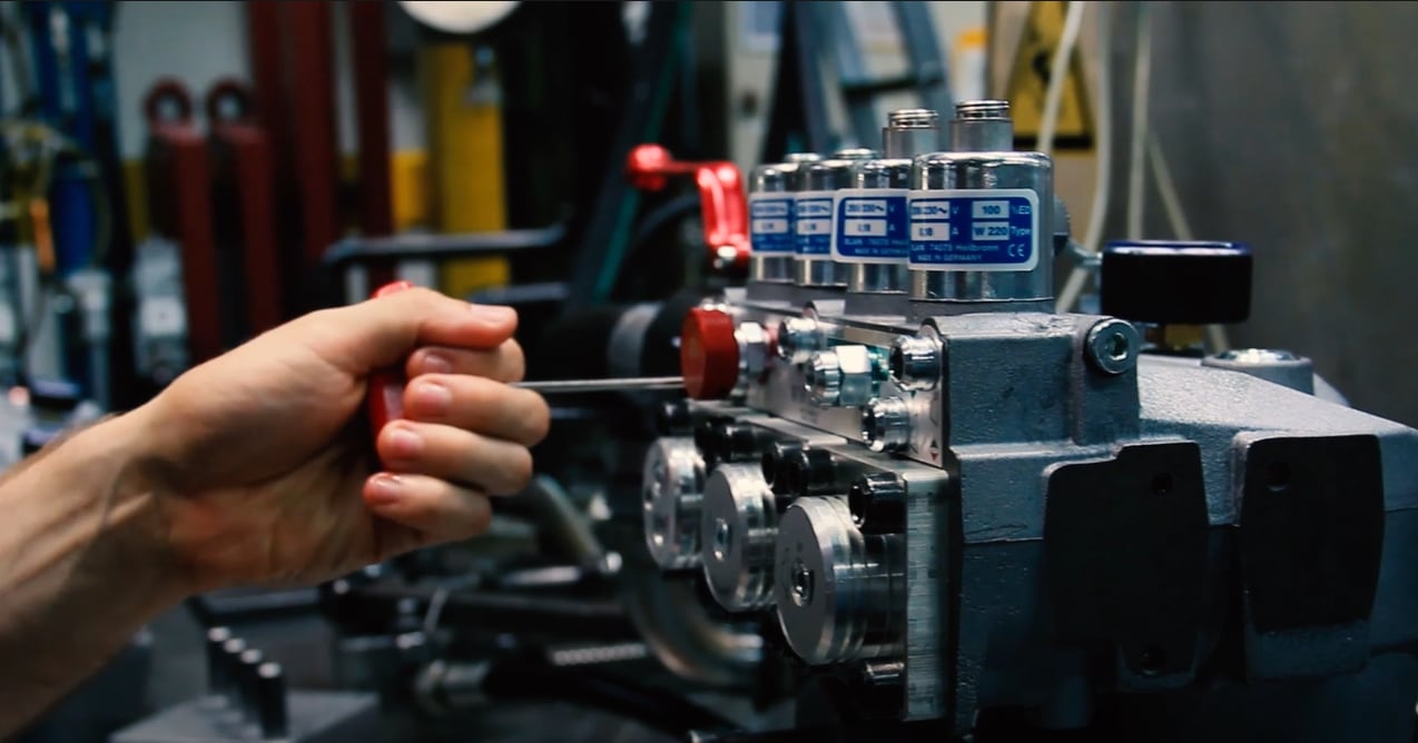 Technician adjusting a Blain hydraulic valve block with a screwdriver