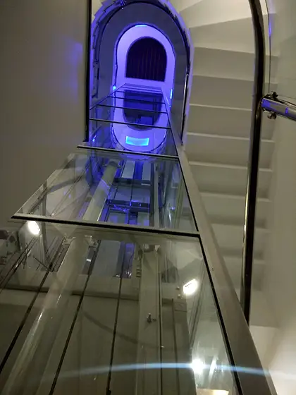 Glass lift and shaft seen from the stairs