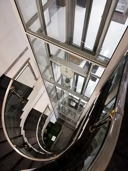 Glass lift and shaft seen from the stairs
