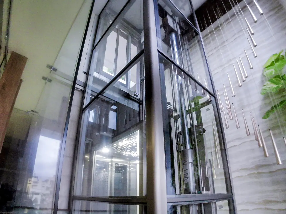 Glass lift shaft rising beside gold pendant lights