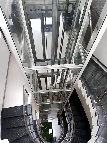 Glass lift and shaft seen from the stairs