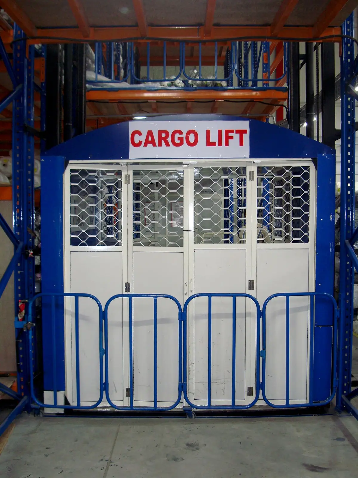 Hydraulic cargo lift cage with a folding gate inside a racking warehouse