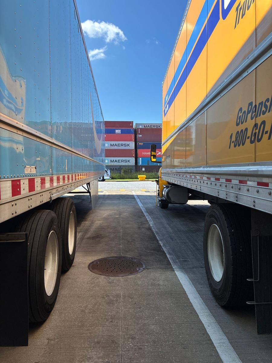 Parked freight trailers with shipping containers behind